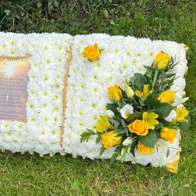 Sunshine Book Pillow - A book-shaped arrangement with a heartfelt message and a cluster of yellow and white flowers, offering a personal tribute.